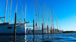 A marina with multiple sailboats docked at wooden piers.