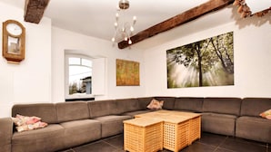 Un salon moderne avec un canapé d’angle, une table basse en bois, une carte accrochée au mur et une grande fenêtre.