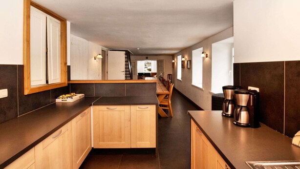 Une cuisine moderne avec des meubles en bois, un long plan de travail et une machine à café.