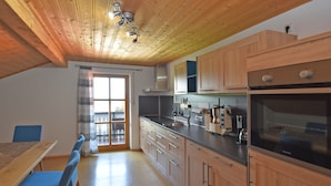 Una cocina con armarios de madera, un lavamanos de acero inoxidable y un horno negro.