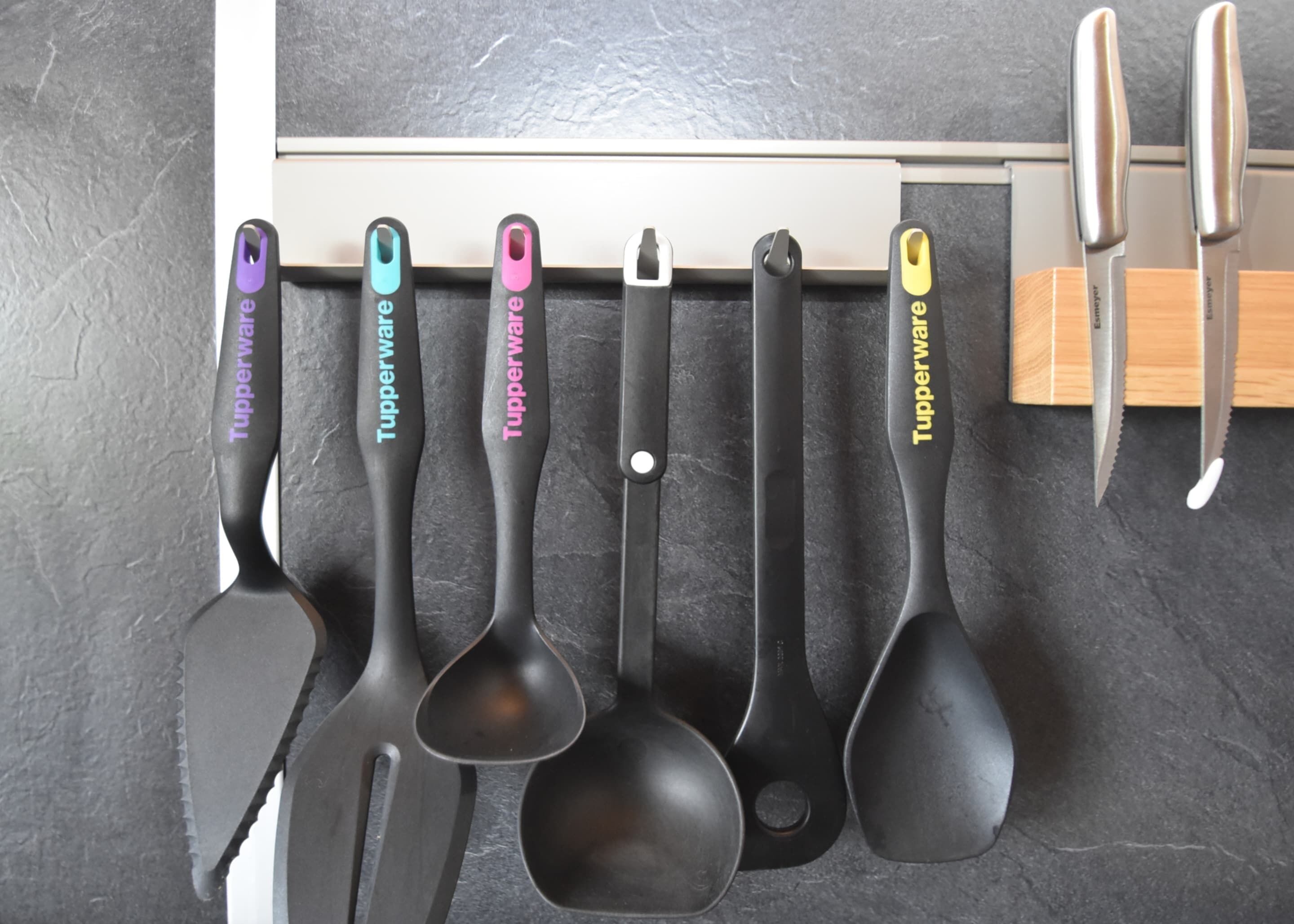 A set of kitchen utensils hanging on a rack.