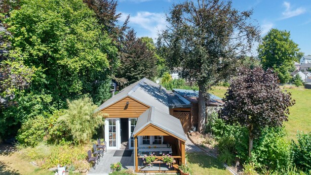 A small house with a sloped roof, surrounded by lush greenery and trees. - Pretty House in the Ardennes With Swimming Pool & Games Room (Waimes)