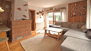 A cozy living room with a fireplace, sofa, and a view of the outdoors. - Mountain Hideaway in Wildenthal (Eibenstock)