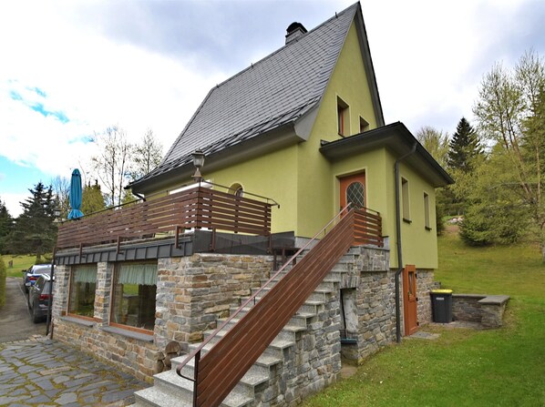 A stone building with a wooden staircase and a metal railing.