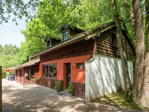 A traditional wooden building with a red facade, a balcony, and a gravel pathway leading to a seating area. - Nature Retreat in Waimes (Waimes)
