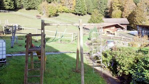 A rural property with a wooden swing set, a fenced area, and a barn.