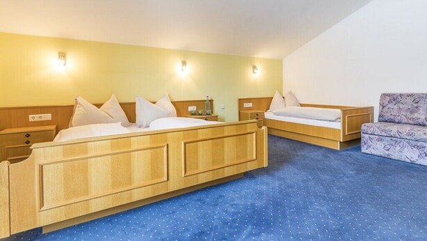 A hotel room with two beds, a sofa, and a small table. - Stadlhof Flachau (Flachau)