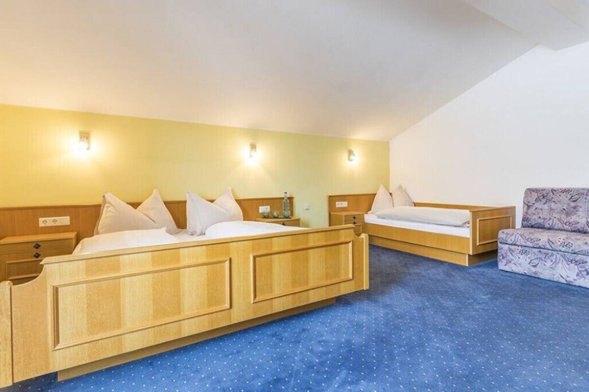 A hotel room with two beds, a sofa, and a small table.