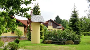 Ein gelbes Haus mit rotem Dach, umgeben von einem gepflegten Garten mit einem Weg zu einer hölzernen Bank.
