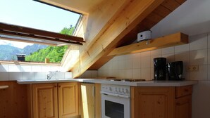 Una cocina con armarios de madera, una estufa y una ventana con vistas a un paisaje montañoso.