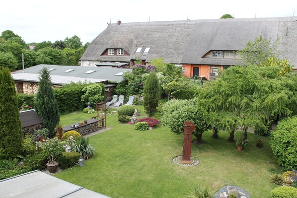 A residential area with a thatched-roof house, a well-maintained garden, and a stone wall. - Apartment in Wittenbeck Near Baltic Sea (Wittenbeck)