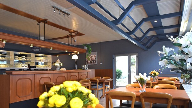 A restaurant with wooden furniture, a bar area, and a view of the outdoors.