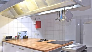 A modern kitchen with white cabinetry, a wooden countertop, and a built-in stove.