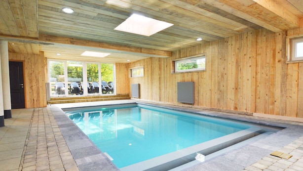 An indoor swimming pool with wooden walls and a tiled floor.