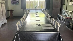 A conference room with a long table, white chairs, and a view of a wooden fence through a large window.