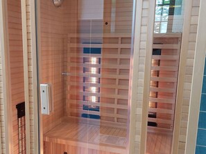 A sauna with a wooden interior and a glass door, featuring a metal rack for towels and a control panel. - Holiday Home With Sauna in the Eifel National Park (Schleiden)