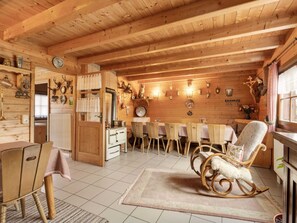 A cozy wooden cabin with a dining area, a kitchen with a stove, and a rocking chair. - Chalet in Hinterrod Thuringen mit Sauna (Eisfeld)