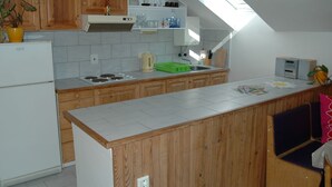 Een keuken met houten kastjes, een inbouwoven, een spoelbak en een dakraam.