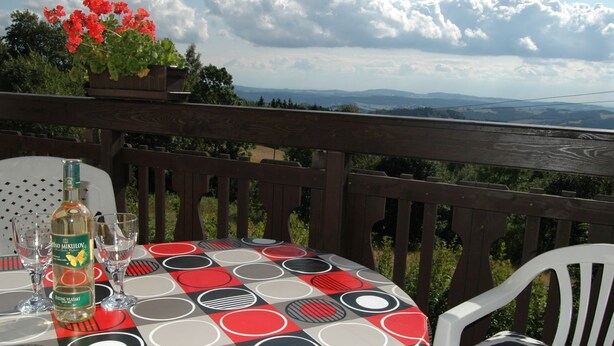 Een tafel buiten gedekt, met drank, glazen en een decoratieve tafelkleed.