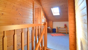 Ein Holzinnenraum mit schrägem Dach, einem Oberlicht, einer Holzwandleiste, einem kleinen Tisch und einem Korb.