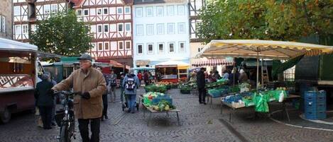 A cobblestone street with market stalls and traditional half-timbered buildings.