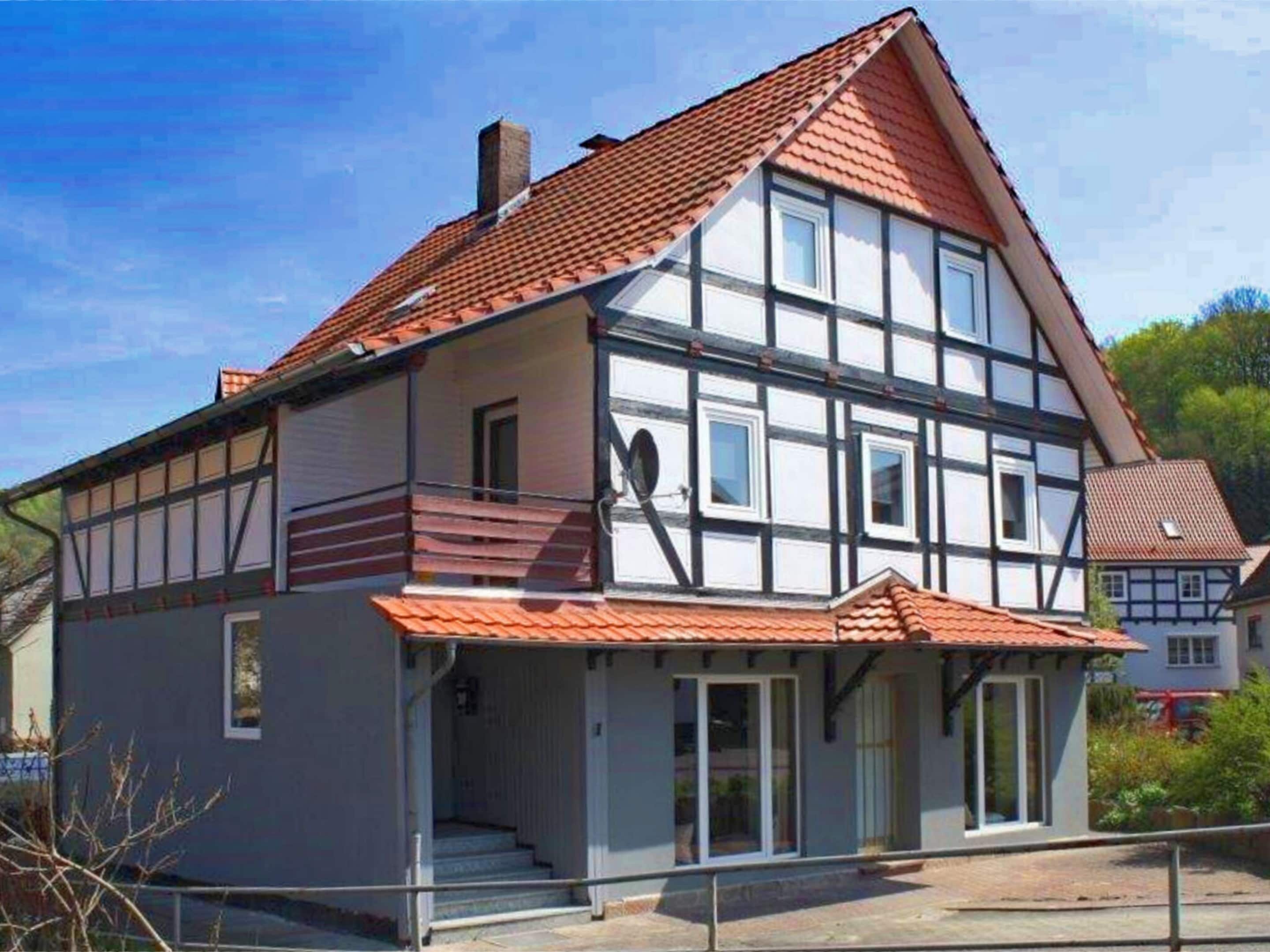 A two-story house with a steeply pitched roof, a balcony, and a front porch.