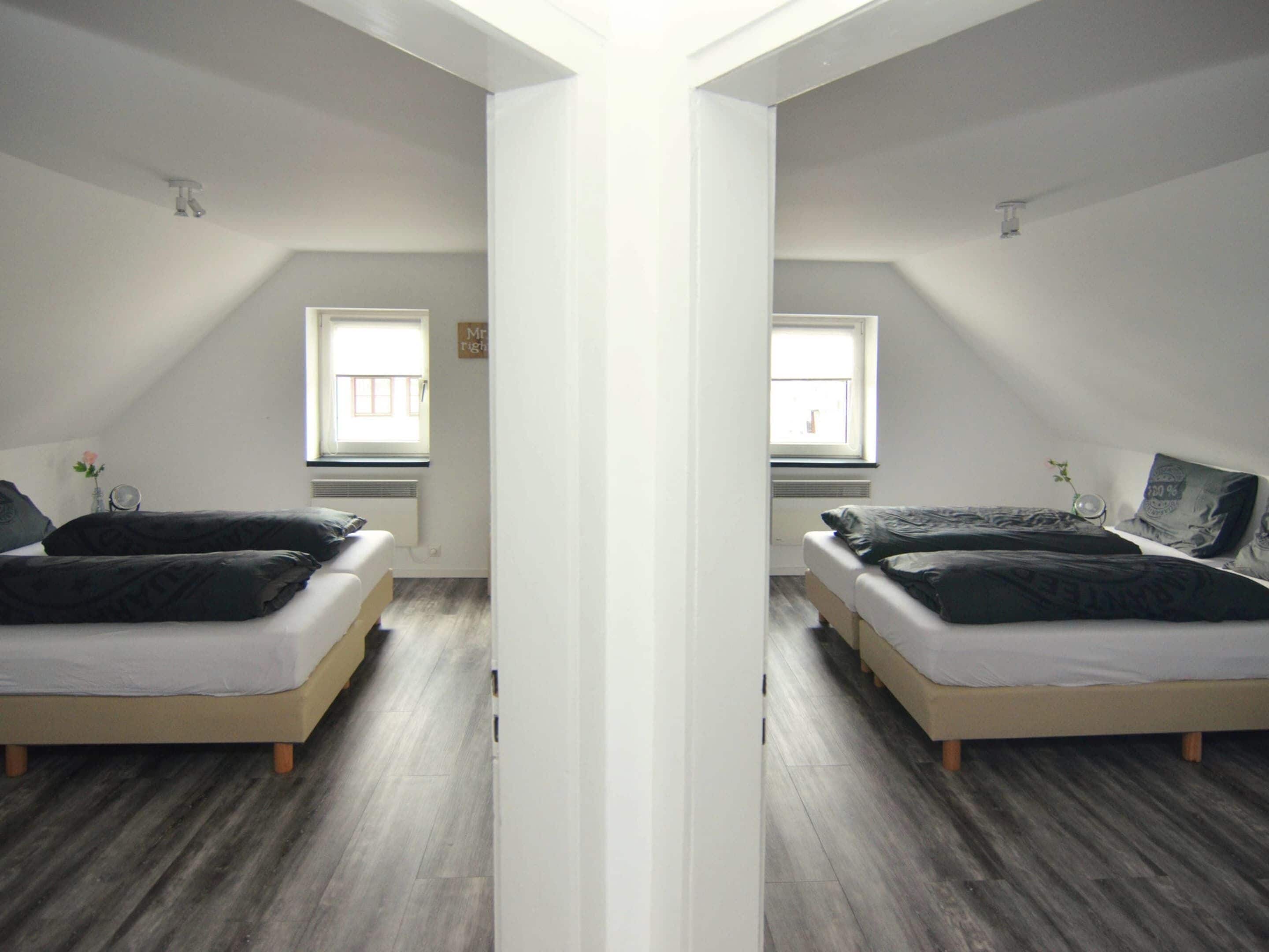 A mirrored room with two beds, a window, and a white ceiling.