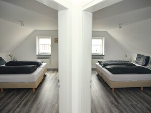 A mirrored room with two beds, a window, and a white ceiling.