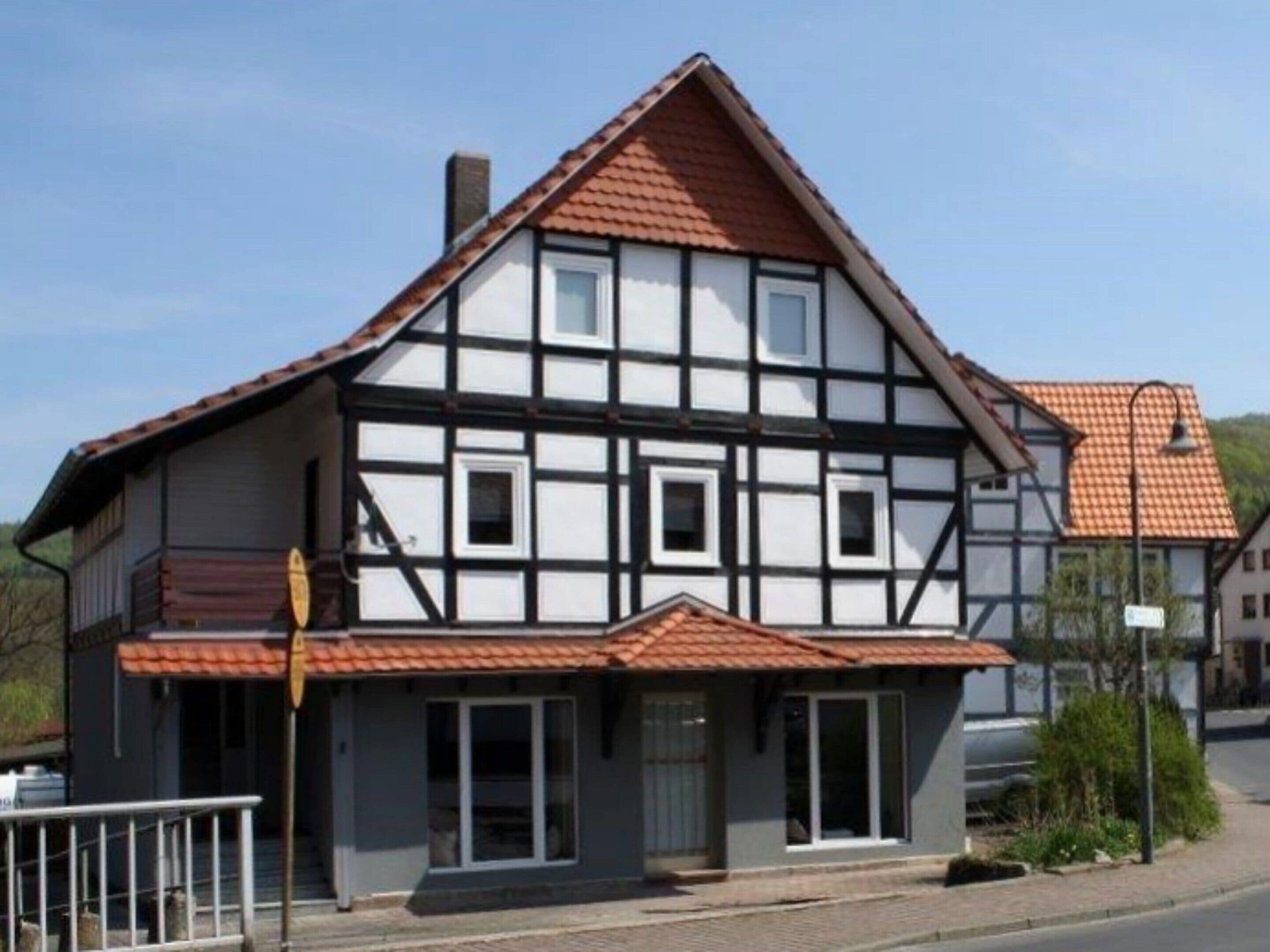 Ein traditionelles Fachwerkhäuschen mit einem steilen Dach, einem markanten Schornstein und einer kleinen Veranda.