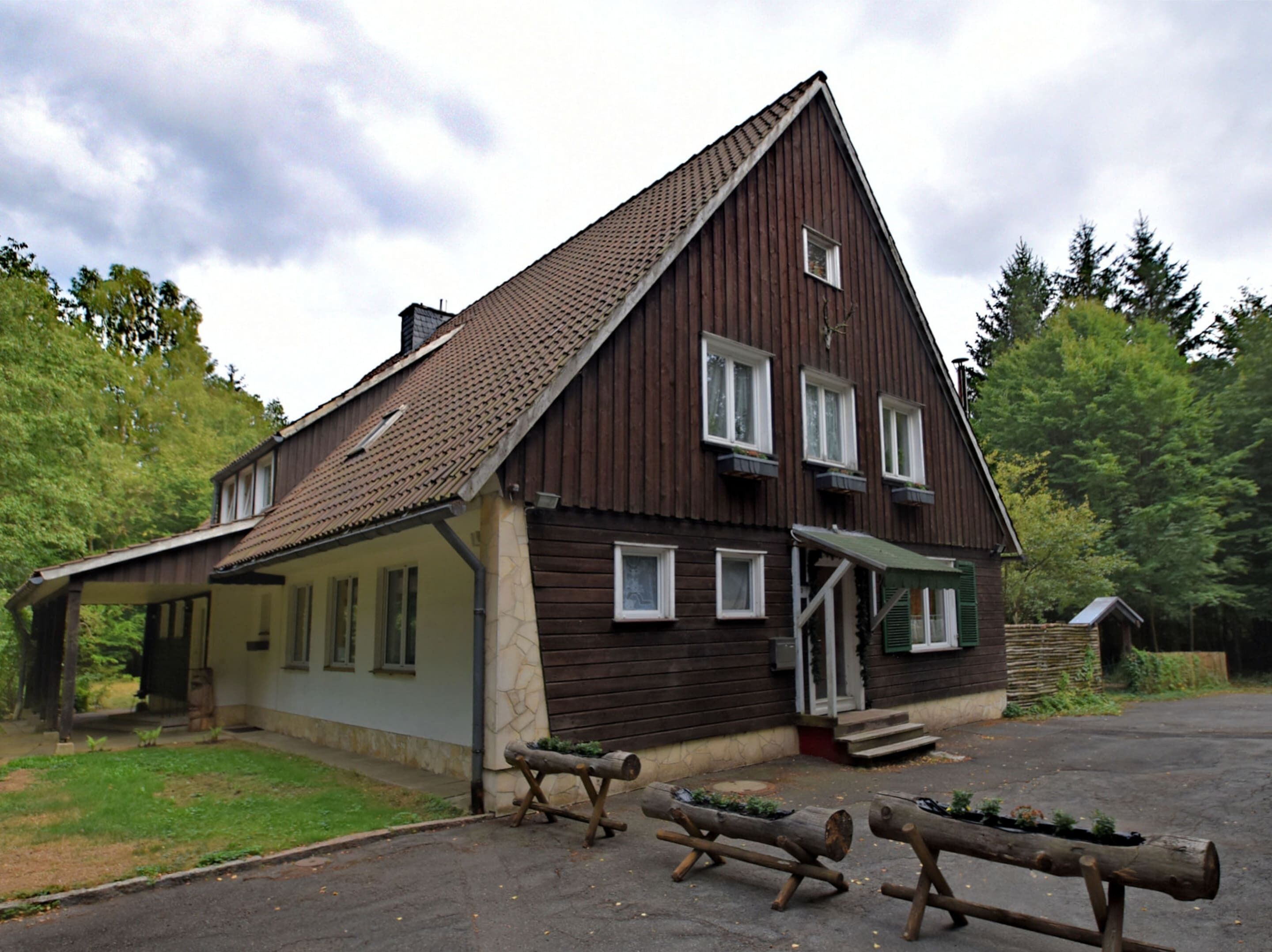A wooden building with a sloped roof, a porch, and a small staircase leading to the entrance.