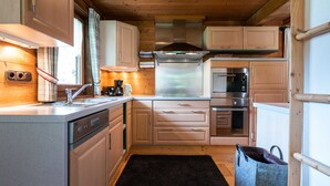 A compact kitchen with wooden cabinets, a stainless steel range hood, and built-in appliances. - Chalet in Kirchberg With Terrace and Garden (Kirchberg in Tirol)