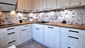 Een moderne keuken met lichte houten kastjes, een steen rugpaneel en een zwarte spoelbak.