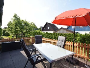 A patio with a table and chairs, an umbrella, and a wooden fence.