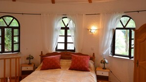 A bedroom with a wooden bed, two nightstands, a wall-mounted lamp, and two windows with curtains. - Strotzbusch Forest Hideaway (Strotzbusch)