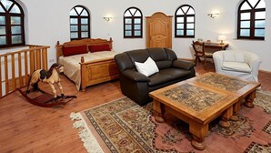 A spacious room with a high ceiling, wooden beams, a large bed, a leather sofa, a wooden table, and a rocking horse. - Strotzbusch Forest Hideaway (Strotzbusch)