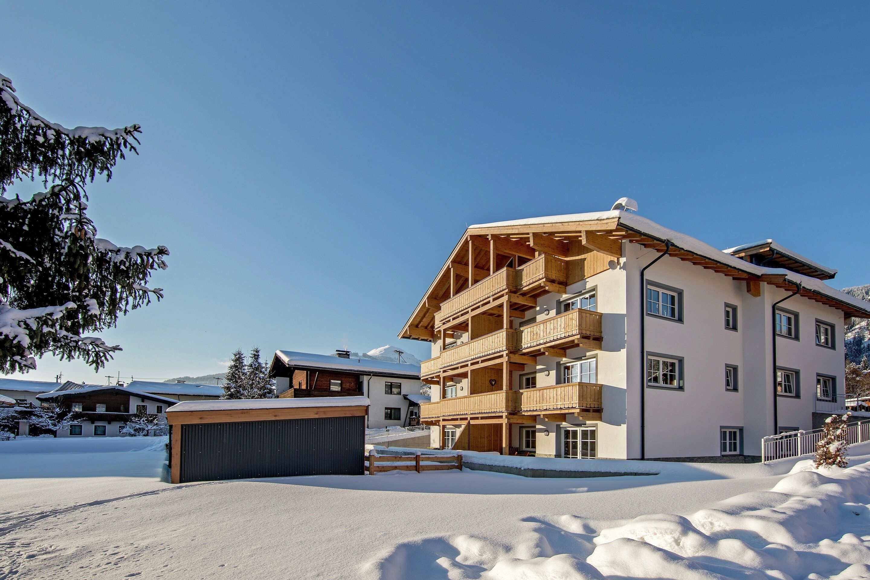 A multi-story building with balconies, a garage, and snow-covered surroundings.