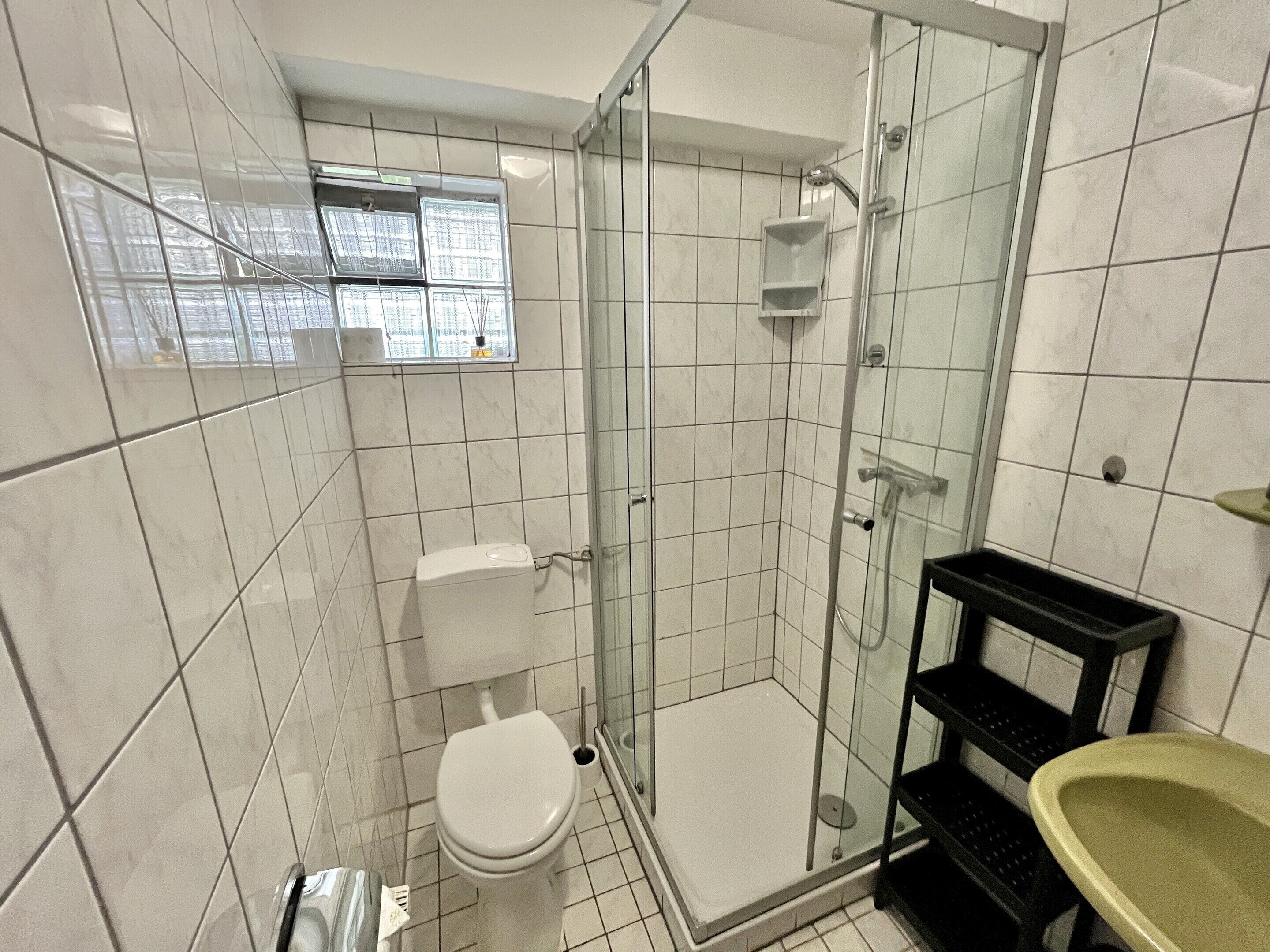 A bathroom with a toilet, a glass-enclosed shower, and a sink.