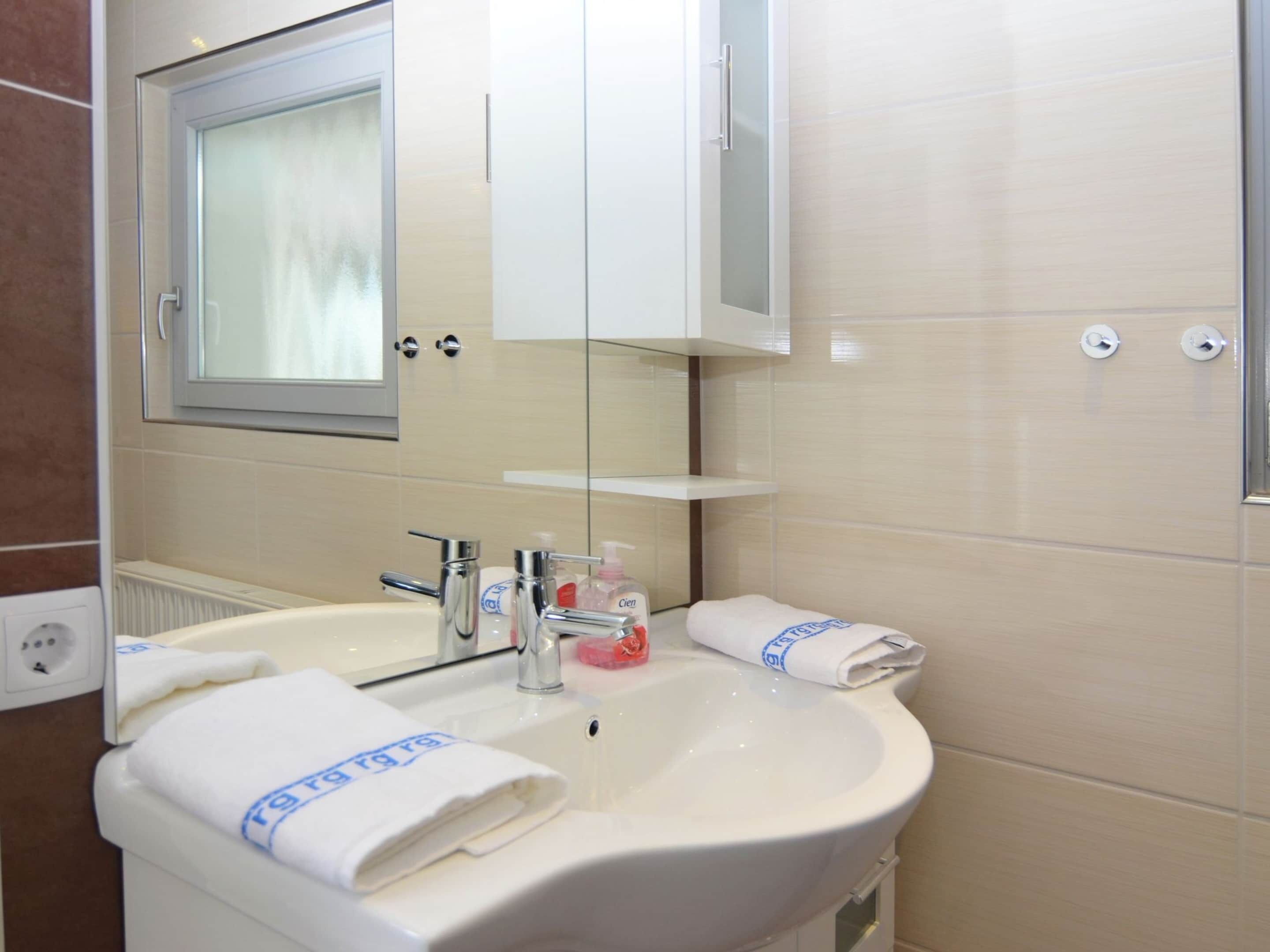 A bathroom with a sink, mirror, and towel rack.