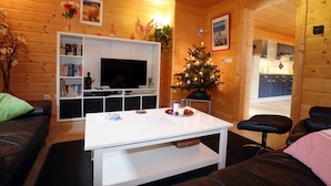 A cozy living room with a white entertainment unit, a flat-screen TV, a Christmas tree, and a fireplace. - Quaint Apartment in Umhausen near Ski Area (Umhausen)