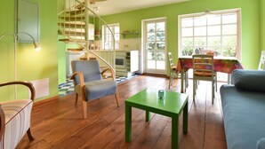 Un soggiorno con una scala a chiocciola, pavimento in legno, un tavolo verde e un divano blu.