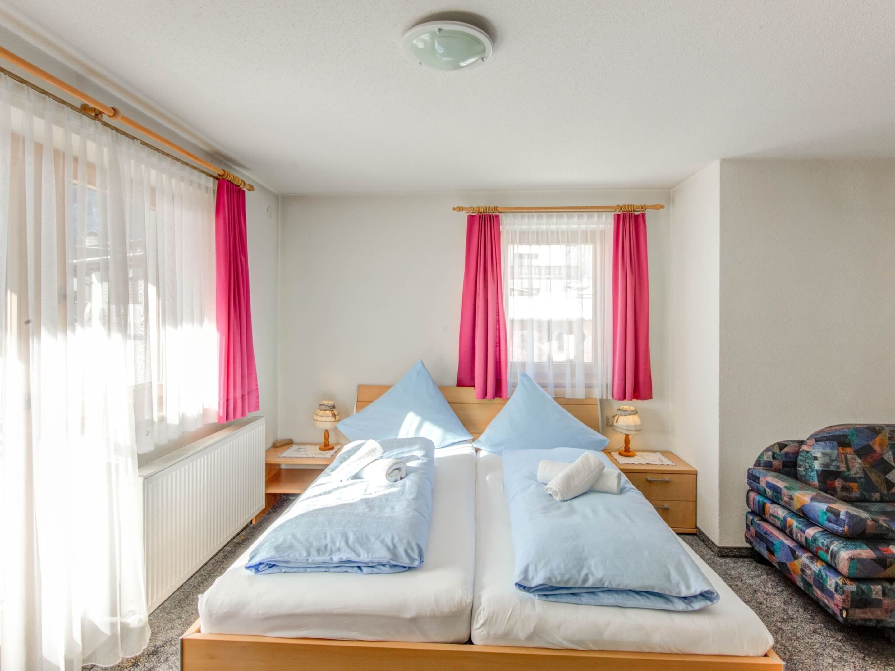 A neatly made bed with blue and white bedding, a wooden headboard, and a bedside table with a lamp.