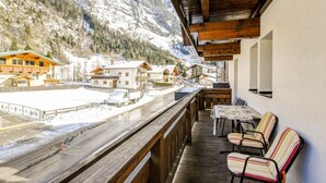 A wooden balcony with a view of a snowy mountain and a town below. - Apartment in Langenfeld Near Solden Ski Lift (Laengenfeld)