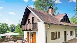 A two-story house with a balcony, a chimney, and a patio with a table and chairs. - Mountains Family Retreat (Rudník)