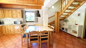 A spacious kitchen with wooden cabinets, a dining table with chairs, and a staircase leading to an upper level. - Mountains Family Retreat (Rudník)