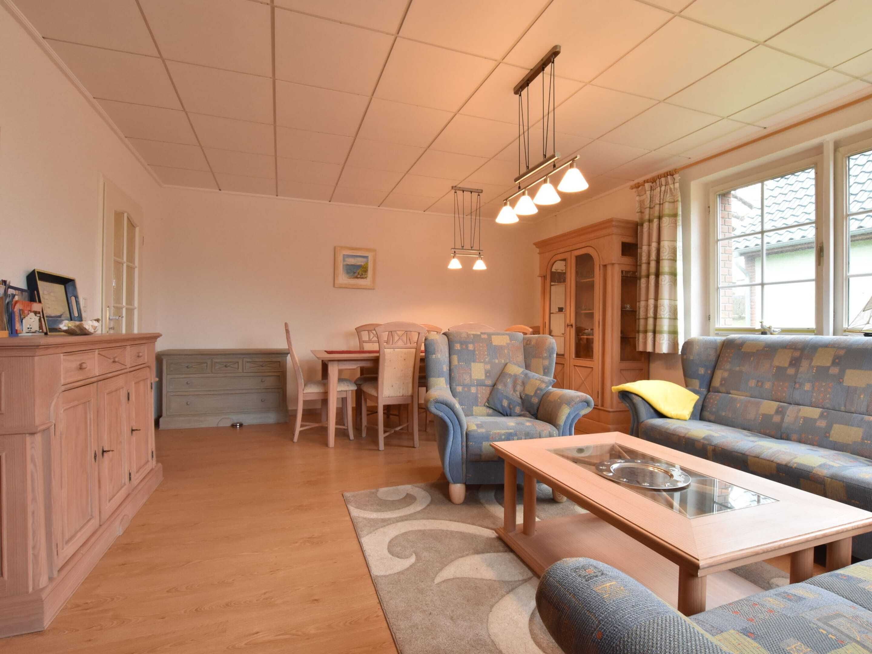 Ein gemütliches Wohnzimmer mit einem Holztisch, einem blau gemusterten Sofa und einem Essbereich mit Tisch und Stühlen.