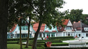 A park with neatly trimmed hedges, benches, and a large tree. - Coastal Retreat in Boltenhagen (Boltenhagen)