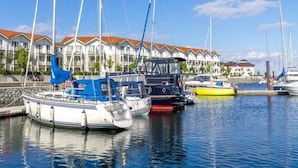 A marina with several boats docked, a row of buildings with red roofs, and a clear blue sky. - Coastal Retreat in Boltenhagen (Boltenhagen)