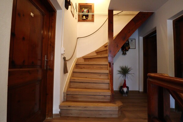 A wooden staircase with a handrail, a potted plant, and a wall-mounted light fixture. - Cozy Farmhouse in Oetz near Ski Area (Oetz)