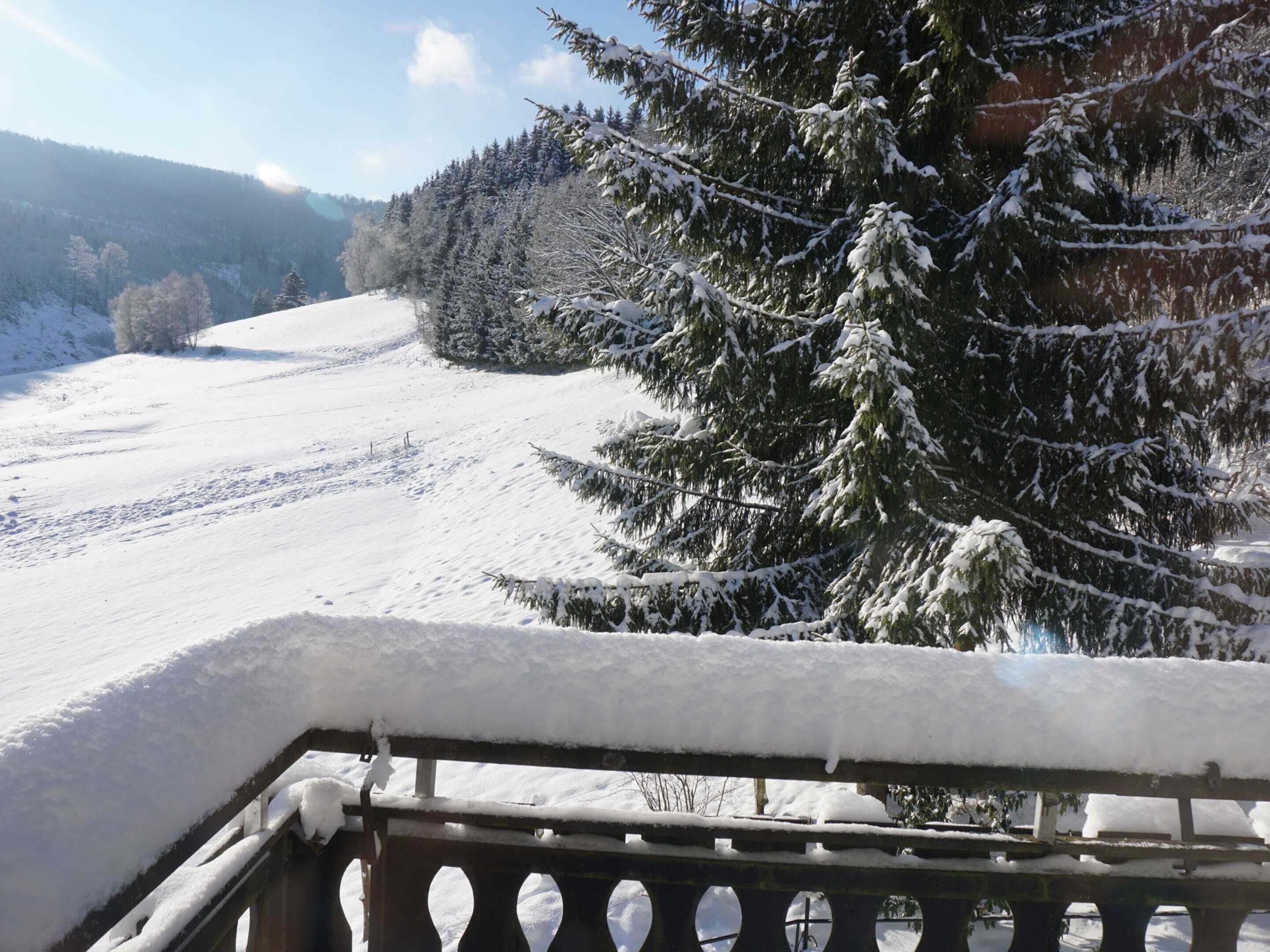 A snow-covered landscape with a wooden railing in the foreground.