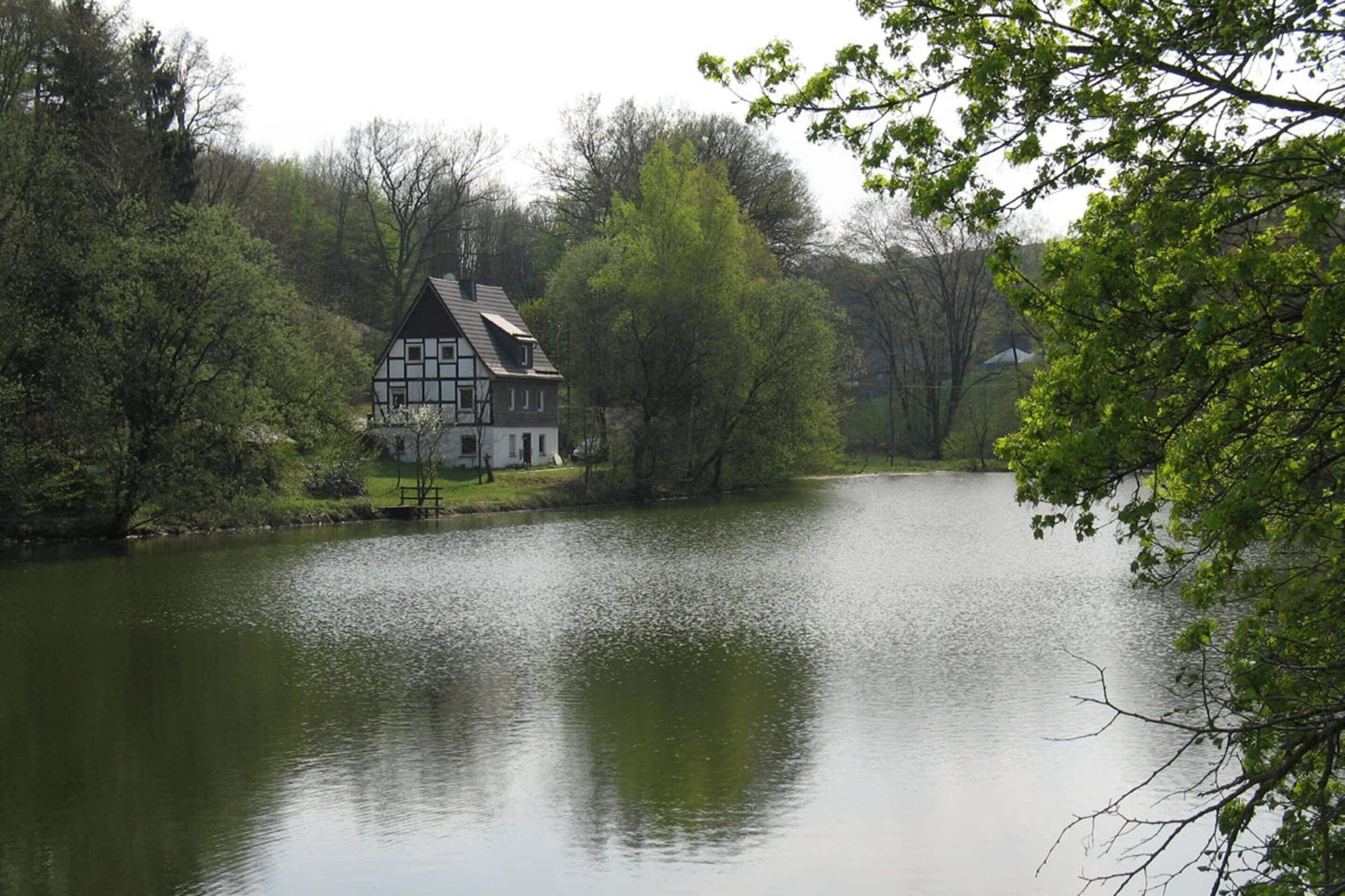 A house by a calm lake surrounded by trees.